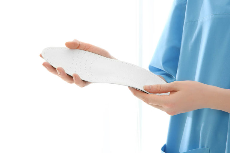 Female orthopedist with insole on white background, closeup